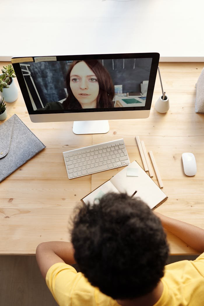 Teenage boy participating in an online class at home, using a desktop computer.